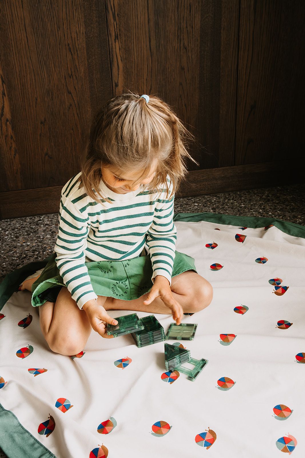 snails toy storage bag and playmat, child is sitting on the mat while playing