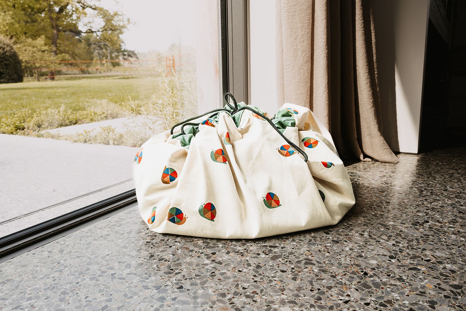snails toy storage bag and playmat, closed back in front of the window