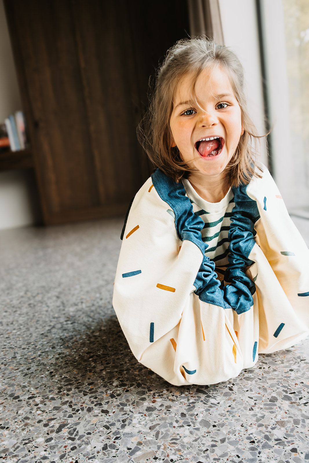 confetti toy storage bag and playmat, child is sitting in the bag