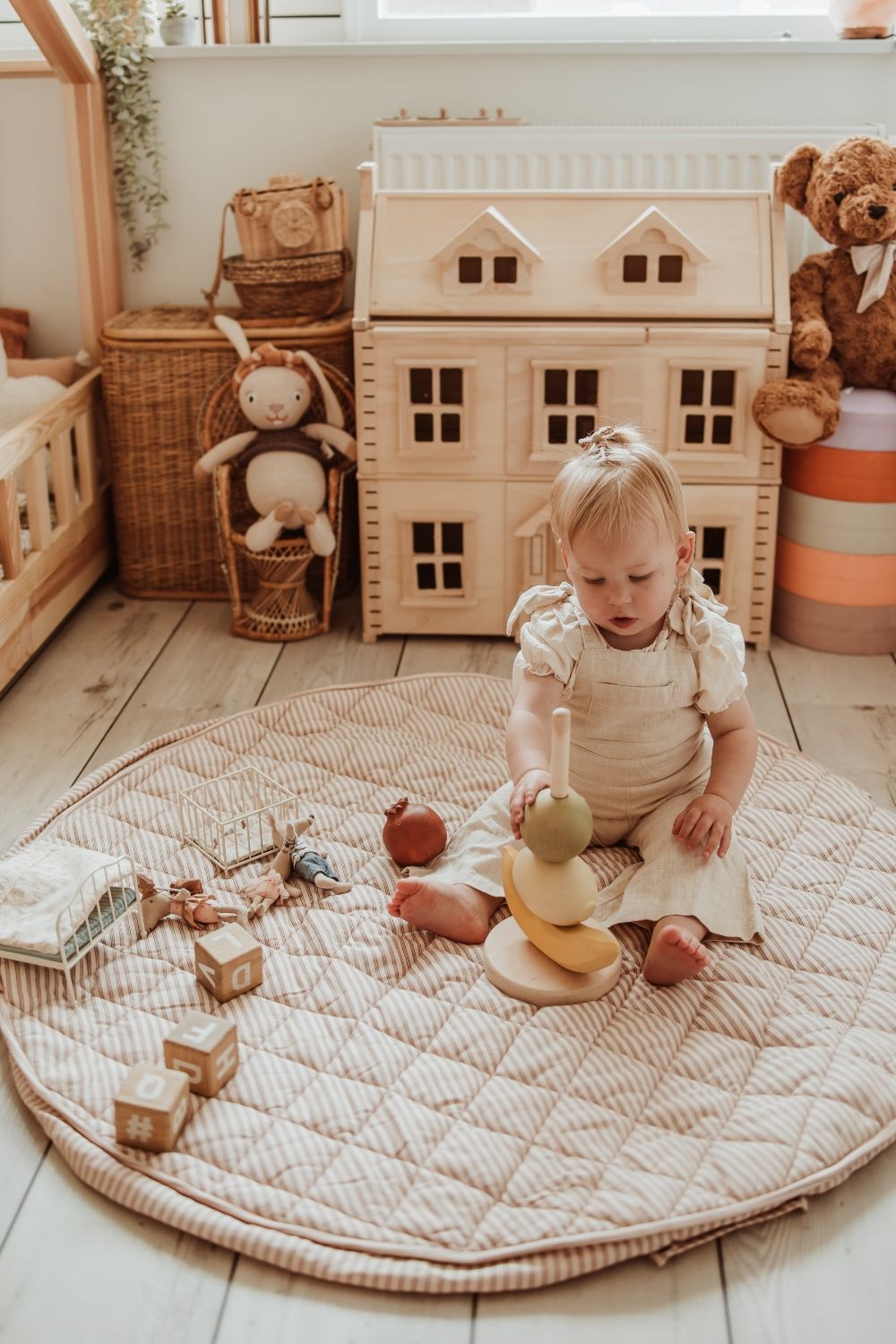soft stripes brown organic babymat, child is sitting on the mat, playing with wooden toys, wooden victorian hous, cuddles