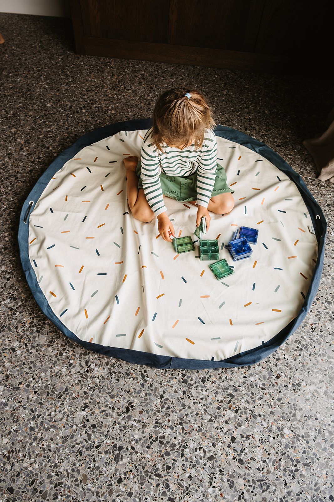 confetti toy storage bag and playmat, child is playing on the open mat