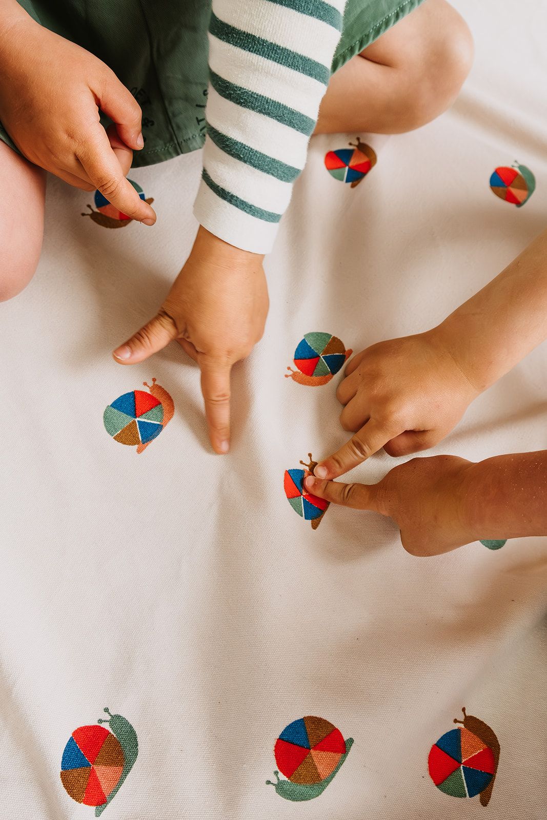 snails toy storage bag and playmat, children are sitting on the mat while pointing at the snails