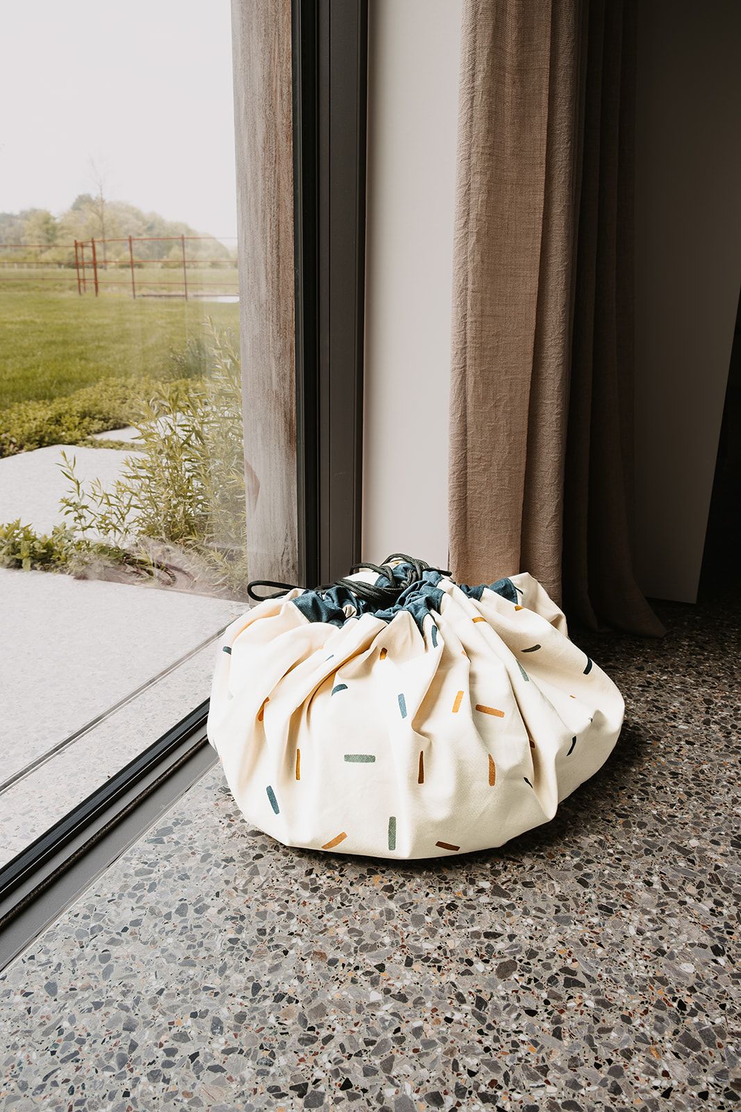 confetti toy storage bag and playmat, closed bag in front of window