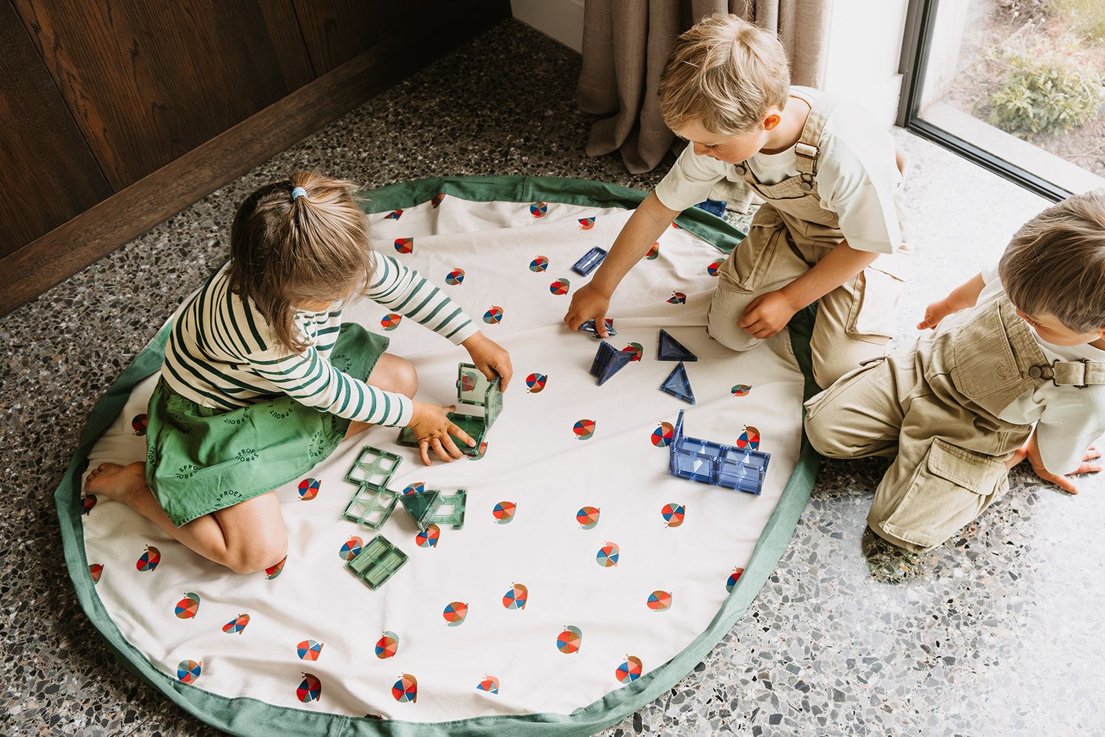 snails toy storage bag and playmat, children are sitting on the mat while playing