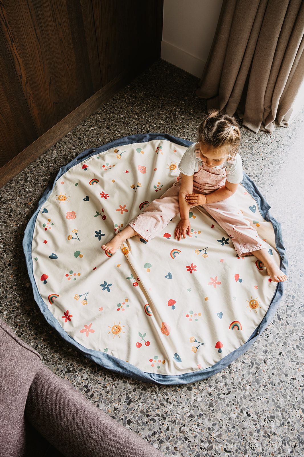 funny days toy storage bag and playmat, open on floor, child is sitting on the mat