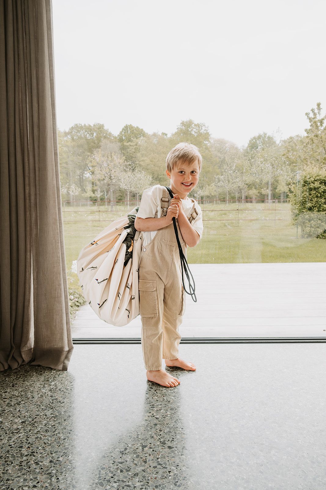 croco toy storage bag and playmat, child is carrying the bag over the shoulder