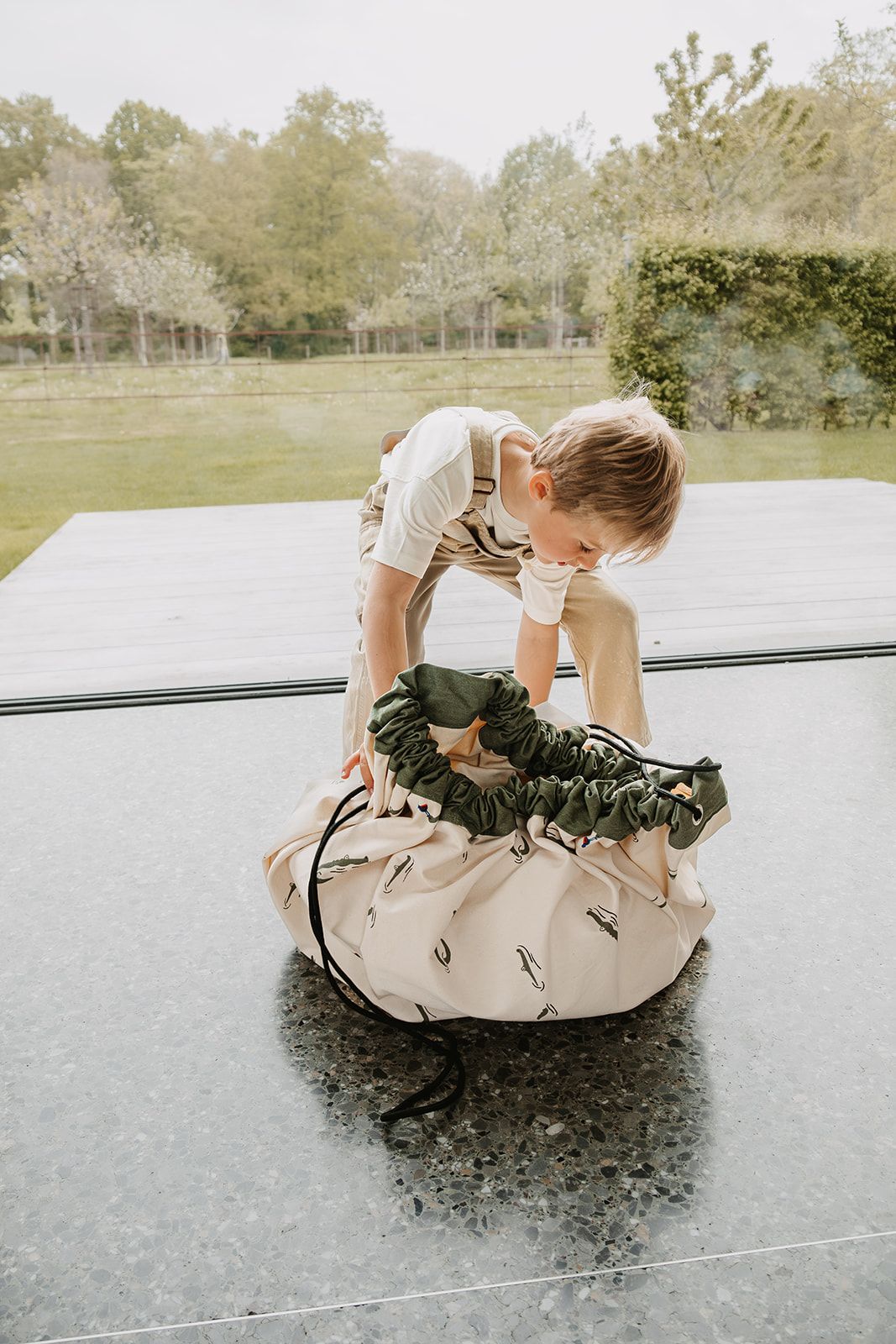 croco toy storage bag and playmat, child is opening the bag