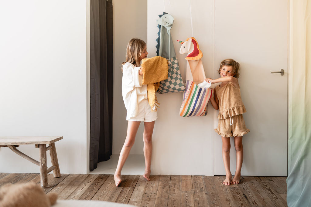 toto unicorn and toto dino, hanging on wall, children are putting blankets in the toto bags