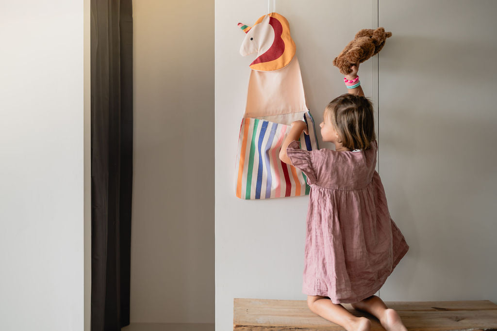 toto unicorn, hanging on the wall, child is putting its cuddle bear in the bag