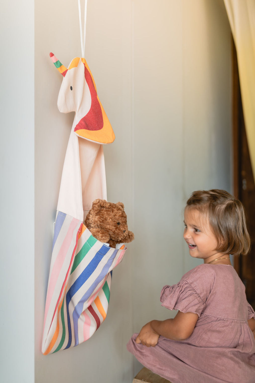 toto unicorn, hanging on wall, child has put its cuddle bear into the bag