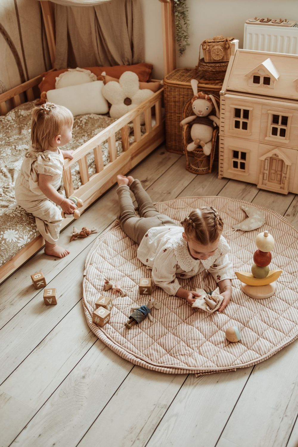 soft stripes brown organic babymat, child is lying on the mat, playing with mouse cuddles, other child is sitting on the bed, victorian playhouse