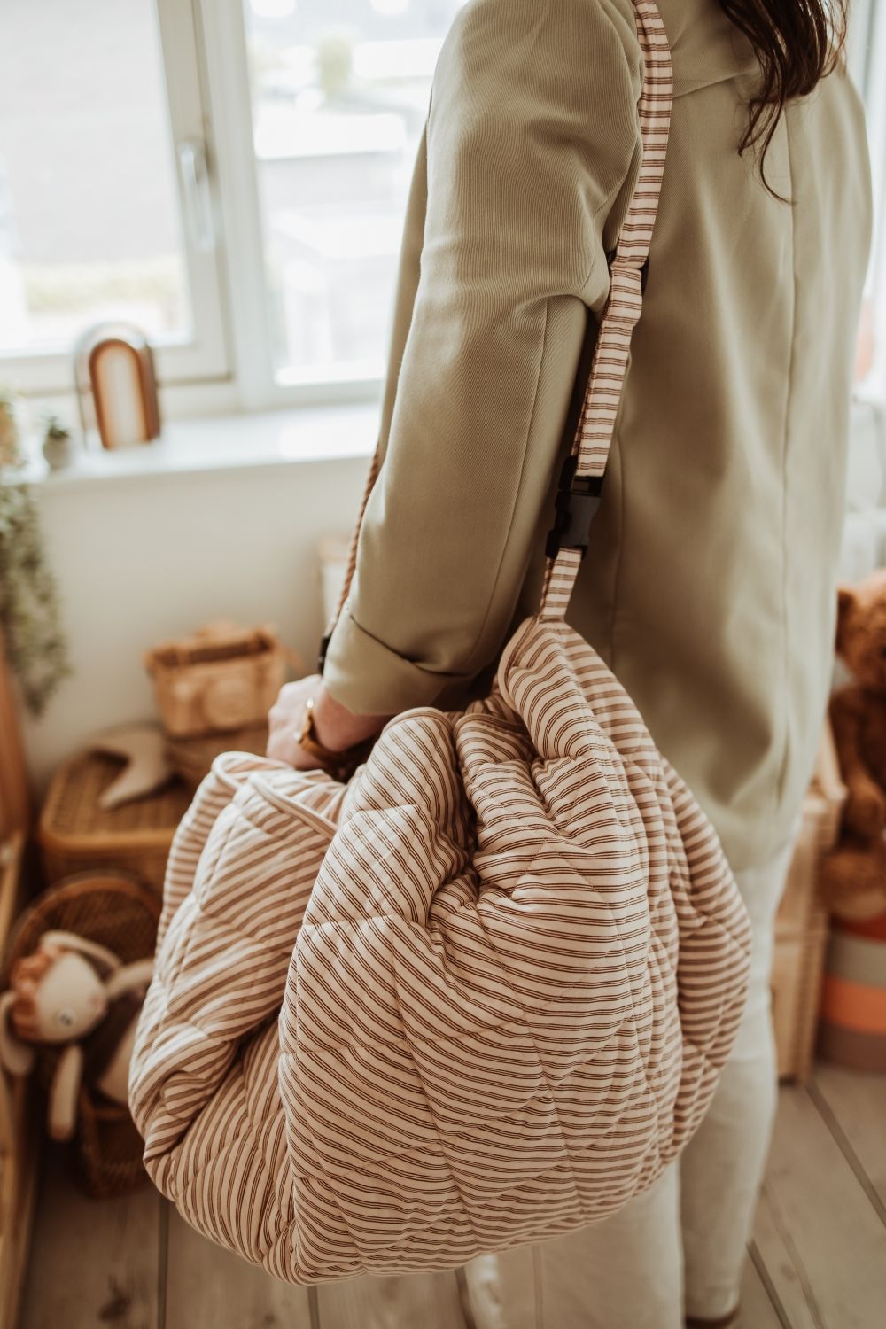 soft stripes brown organic babymat, person is carrying the bag with the shoulder strap