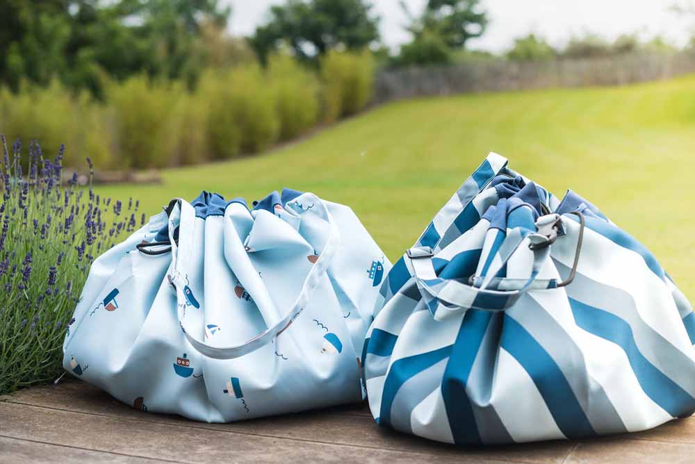 outdoor storage bags blue/green stripes and little boat print, closed bags standing next to each other on terrace in garden