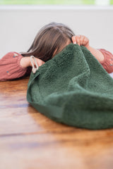 noomad soft teddy evergreen, child is looking into the packaging of the mat