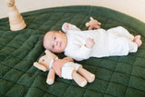 noomad soft teddy evergreen, baby is lying on the open mat, awake, cuddles and wooden toy