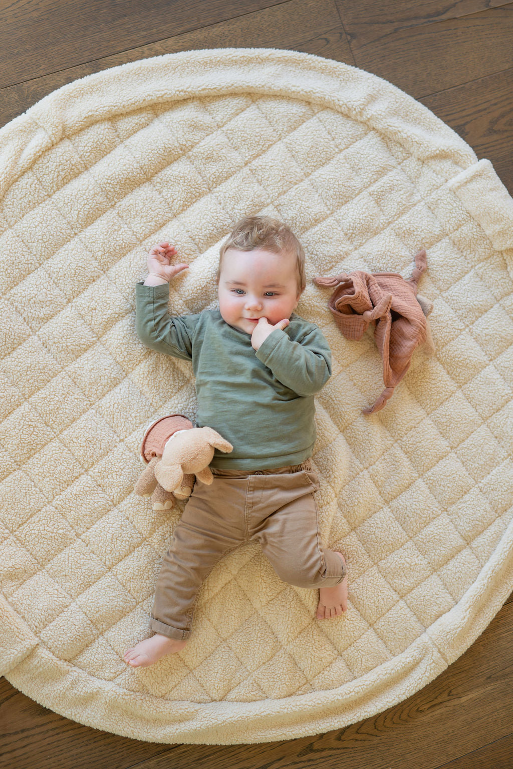 noomad soft teddy oak, baby is lying on the mat between soft cuddles