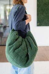 noomad soft teddy evergreen, adult is carrying the closed bag on the shoulder