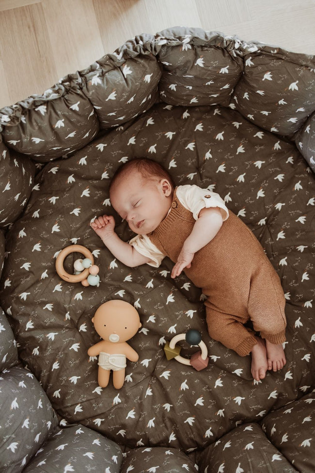 bloom birds babymat, crib, raised edges, little baby is sleeping in the crib, wooden toys and doll