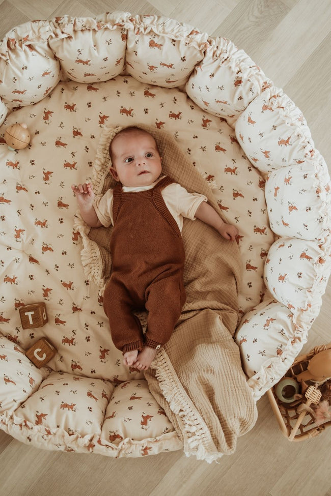 bloom rabbit babymat, crib, raised edges, baby is lying in the crib on blanket, wooden toys