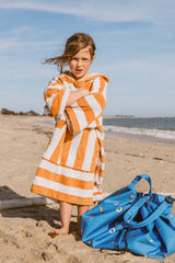 swim fun outdoor beach bag, child is standing in the sand, covered in a towel, standing next to the bag