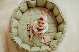 Bloom meadow green organic babymat, raised edges, child sitting on mat between toys, looking up