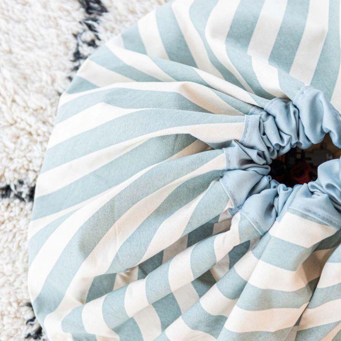 detail picture toy storage bag and play mat, green stripes, closed bag on white carpet